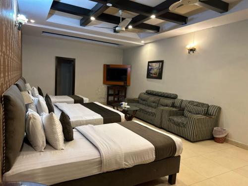 a hotel room with two beds and a couch at Royal Ilva Hotel in Lahore
