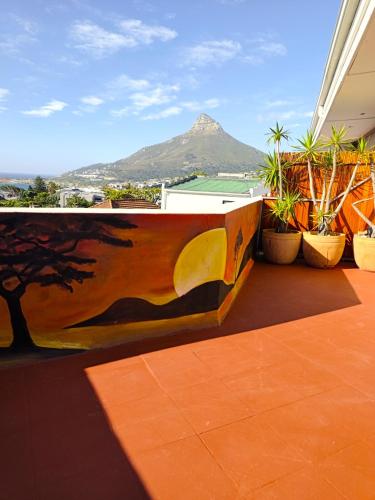 a painting on a wall on a balcony with a mountain at African Groove Camps Bay in Cape Town