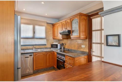 eine Küche mit Holzschränken, einer Spüle und einem Kühlschrank in der Unterkunft Villa Tania - Villa independiente con piscina privada in Playa Blanca