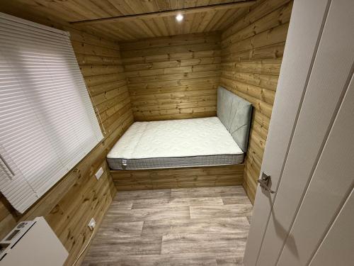 een kleine kamer met een bed in een houten huis bij Stately Stables Camping Site in Winslow