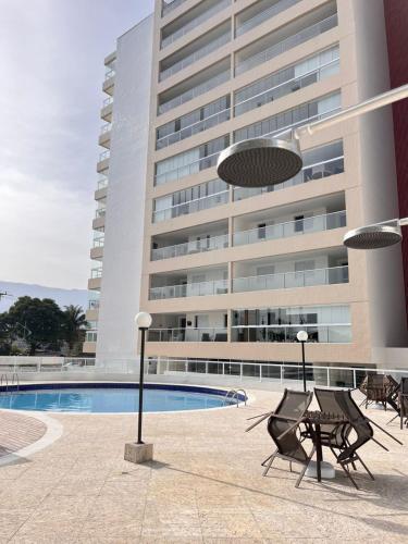 um prédio com piscina e cadeiras em frente a um prédio em Apartamento a 500m da praia de Bertioga em Bertioga