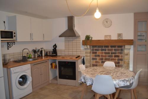 La Blanche des Marais, maison de ville في Picauville: مطبخ مع طاولة وطاولة وكراسي