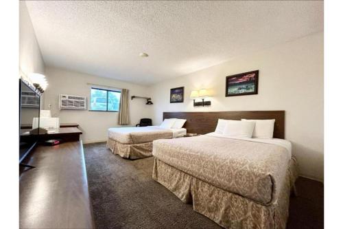 a hotel room with two beds and a television at Homestead Inn Wolf Point Hwy 2 in Wolf Point