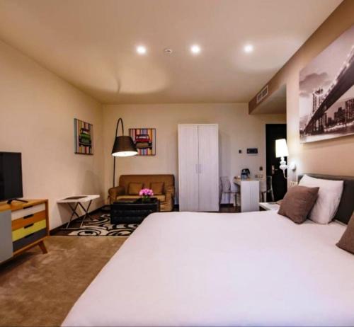 a bedroom with a large white bed and a living room at Pegass hotel in Yerevan