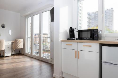 a kitchen with white cabinets and a large window at Studio le Goya - Cosy & Lumineux in Thionville