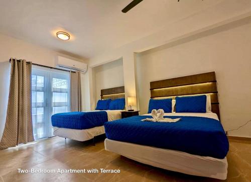 Un dormitorio con dos camas con sábanas azules y una ventana. en Ocean Front Apartments, en Arecibo