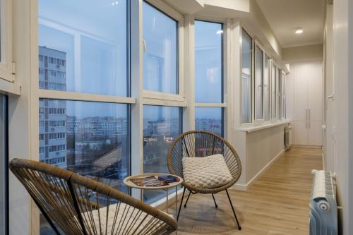 une chambre avec deux chaises, une table et des fenêtres dans l'établissement Soul Rentals 2BR Cozy Apt, New Block & Calm Gem, à Chişinău