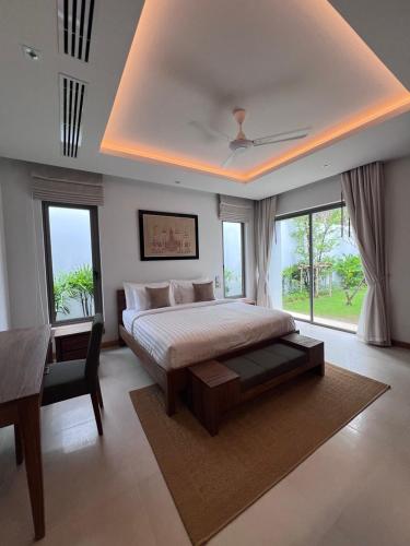 a bedroom with a bed and a desk and windows at Grand garden villa in Phuket