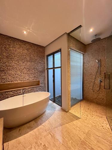 a bathroom with a tub and a glass shower at Grand garden villa in Phuket