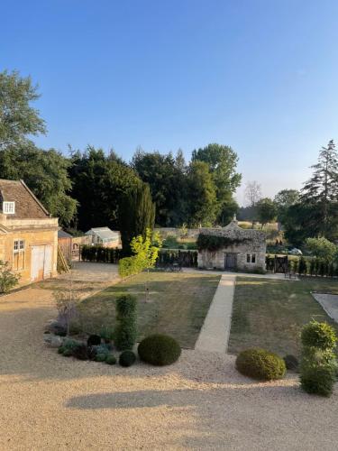 un jardín con un edificio de piedra y una casa en The Green, en Wingfield
