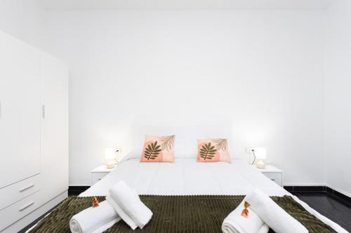 Dormitorio blanco con cama blanca y almohadas rosas en Apartamento Campo Rosa Tacoronte, en Tacoronte