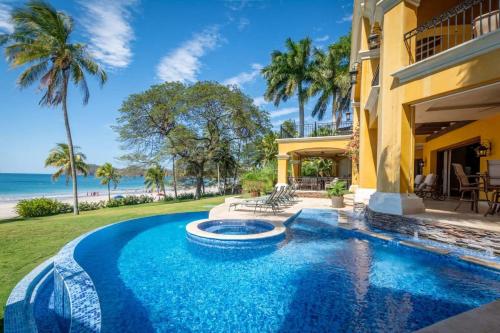 uma piscina em frente a uma casa com praia em Spectacular Mediterranean-Style Mansion with Beachfront Views in Playa Flamingo em Playa Flamingo
