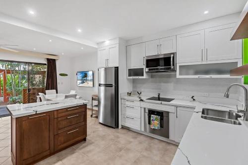Una cocina con gabinetes blancos y electrodomésticos de acero inoxidable. en Colorful & Private 2-Bedroom Condo Just a Short Walk from the Beach, en Coco