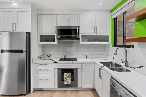 Una cocina con gabinetes blancos y un refrigerador de acero inoxidable. en Colorful & Private 2-Bedroom Condo Just a Short Walk from the Beach, en Coco