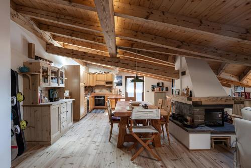 una cucina con soffitti in legno, tavolo e sedie di Mansarda di charm Valli di Borzago a Mortaso