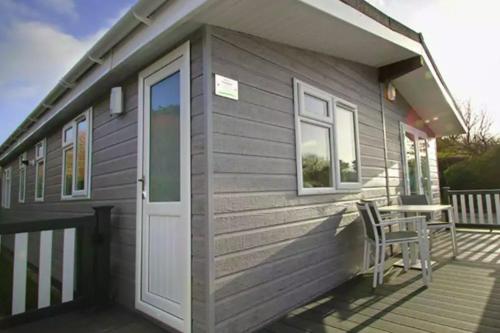 a tiny house with a door and a chair on a deck at 4 Bedroom Select Lodge with Park Facilities in Milford on Sea