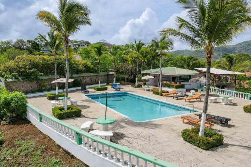 a swimming pool with palm trees in a resort at Tropical Condo with Spectacular Ocean Views, Panoramic Dining Terrace & Quick Walk to Beach in Coco
