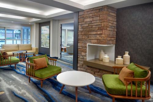a lobby with chairs and a brick fireplace at Fairfield Inn & Suites by Marriott Frederick in Frederick