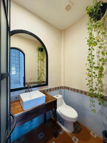 a bathroom with a sink and a toilet and a mirror at Hotel Tulum Centro, Party Hotel in Tulum