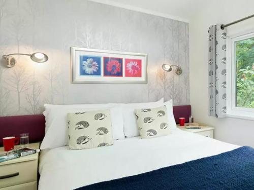 ein Schlafzimmer mit einem weißen Bett mit Kissen und einem Fenster in der Unterkunft Merley Woodland Signature 2 Lodge with Hot Tub in Wimborne Minster