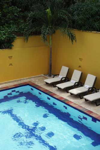 a pool with lounge chairs and a palm tree at Curazao Hotel -Centro Histórico- in Santa Fe de Antioquia