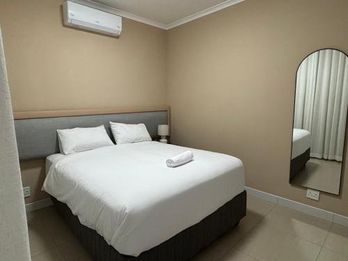 a bedroom with a large white bed and a mirror at The Onyx Luxury Apartment in Windhoek