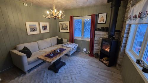 Una sala de estar con un sofá y una chimenea. en Fox Cabin, en Lyngen