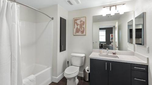 a white bathroom with a toilet and a sink at Landing Apartments - Spring, TX in The Woodlands