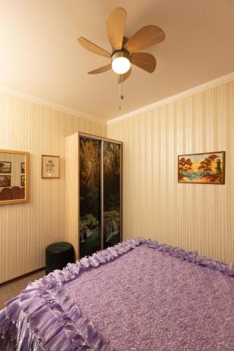 a bedroom with a purple bed with a ceiling fan at Apartment Amber Riga in Riga