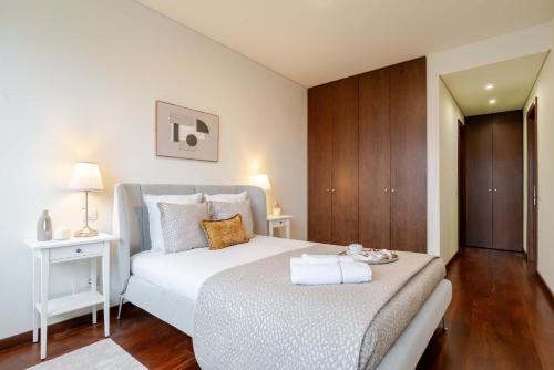 a bedroom with a large white bed and wooden floors at Modern & Spacious Flat with Garage by HostWise in Vila Nova de Gaia