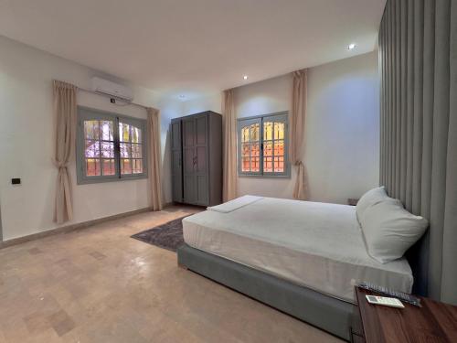 马拉喀什Charmante villa avec piscine privée et jardin的一间带一张大床和两扇窗户的卧室