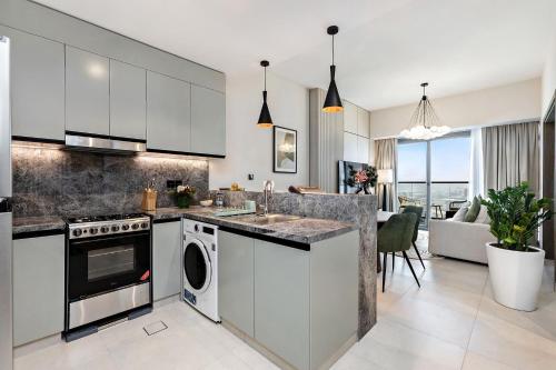 a kitchen with white cabinets and a sink and a dishwasher at Stylish 1BR Apartment at Damac Hills Golf Gate in Dubai
