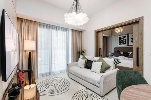 a living room with a couch and a bedroom at Stylish 1BR Apartment at Damac Hills Golf Gate in Dubai