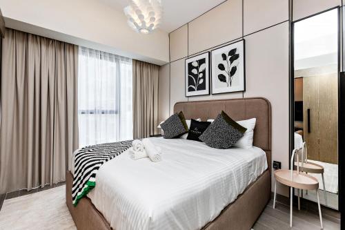 a bedroom with a large bed and a table at Stylish 1BR Apartment at Damac Hills Golf Gate in Dubai