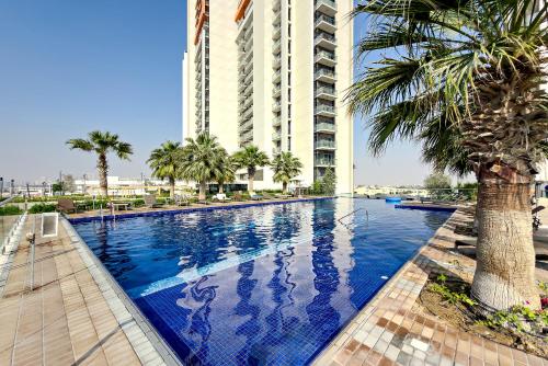 a swimming pool in front of a tall building at Stylish 1BR Apartment at Damac Hills Golf Gate in Dubai