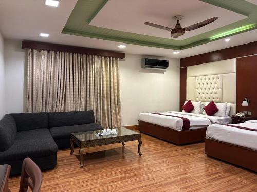 una habitación de hotel con dos camas y un sofá en Ilva Hotel, en Lahore
