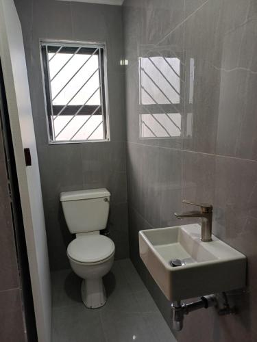 a bathroom with a toilet and a sink and a window at Halaal Serenity 3bedroom 6sleeper in Cape Town