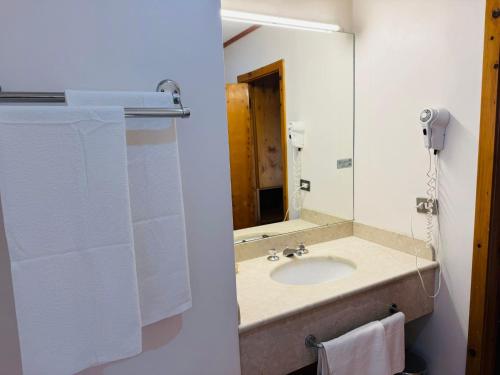 un bagno con lavandino, specchio e asciugamani di Eurotel Cermis a Cavalese