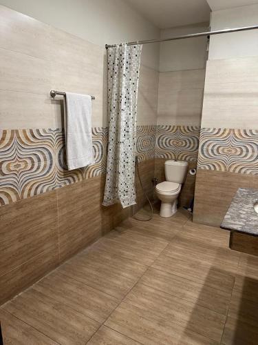a bathroom with a toilet and a shower curtain at Ilva Hotel in Lahore