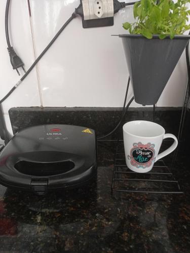 a black toaster and a cup of coffee on a counter at Quarto Aconchegante in João Pessoa