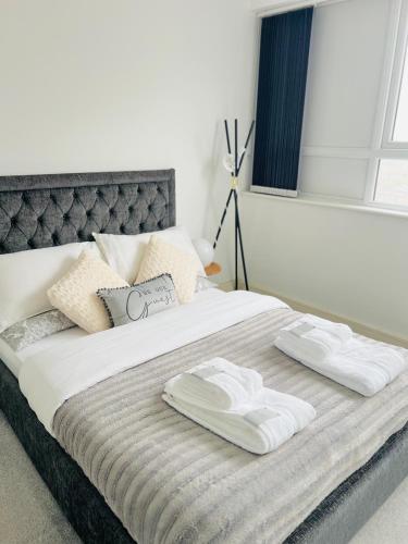 un letto con due asciugamani sopra di Maidstone Town Centre, 2 Bedroom Apartments, Convenient Includes every essential a Maidstone