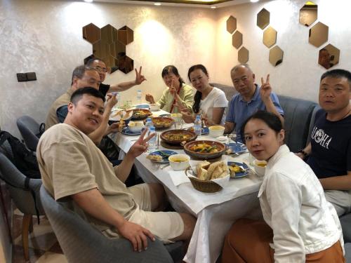 Hotel Dar Annasr في شفشاون: مجموعة من الأشخاص يجلسون حول طاولة ويتناولون الطعام