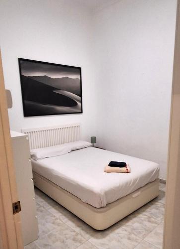 a bedroom with a white bed with a picture on the wall at Marvelous flat in the city center in Ceuta