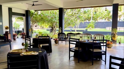 a restaurant with black tables and chairs and windows at The Colony Hotel in Habaraduwa