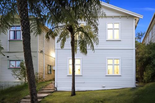 a white house with two palm trees in front of it at Skyline Urban - Entire Apartment with View, Netflix, Nespresso, and Street Parking in Wellington