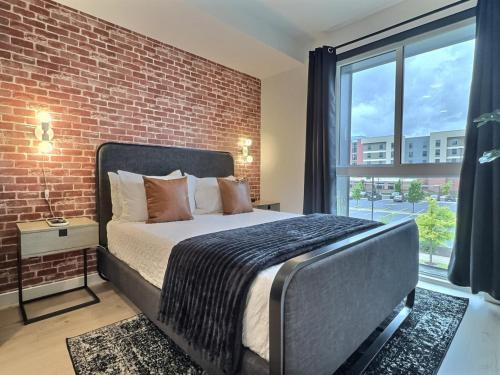 a bed in a room with a brick wall at Railroad Park Reset, Modern Space in Birmingham