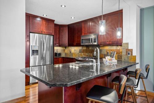 坎莫尔Luxurious Condo Mountain Views Hot-tub and Billiards的厨房配有花岗岩台面和木制橱柜