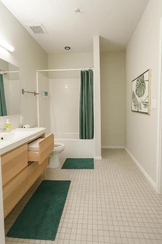 a bathroom with a toilet and a green shower curtain at Forestline Suite in Des Moines