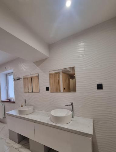 a white bathroom with two sinks and a mirror at stary PGR rooms & hostel in Grabik