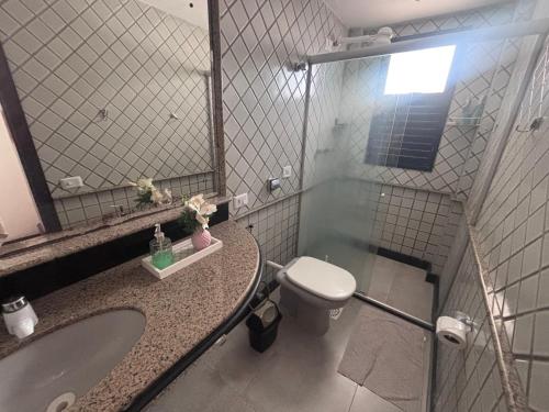 a bathroom with a toilet and a sink and a mirror at Carnatal Agora- 30m da Arena das Dunnas in Natal